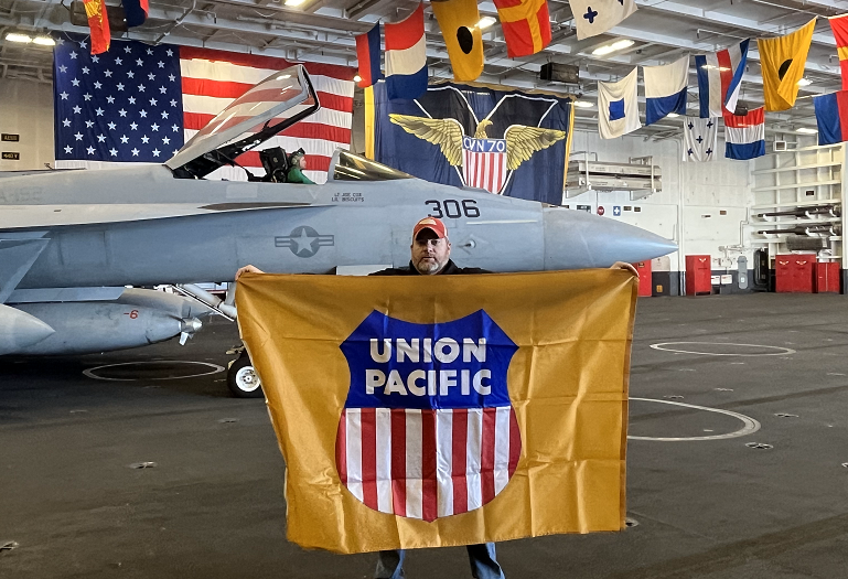 Mark Karpf holds a UP Flag in the hangar of USS Carl Vinson | LR