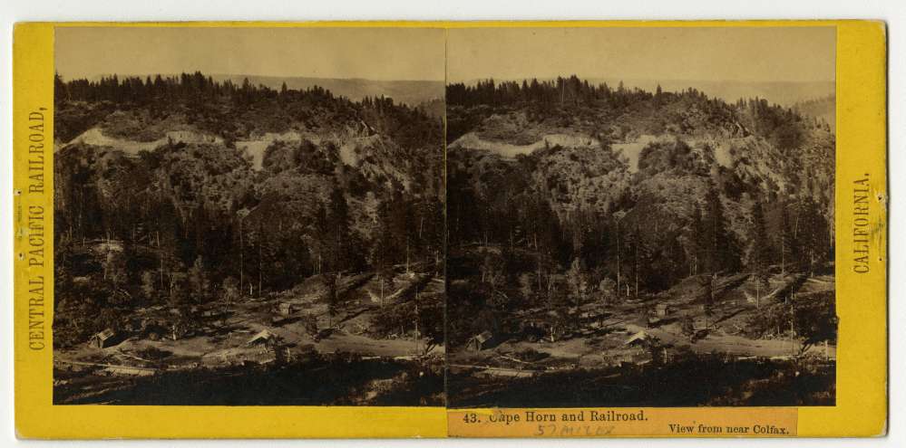 A stereo card of small buildings are near the railroad tracks at Cape Horn
