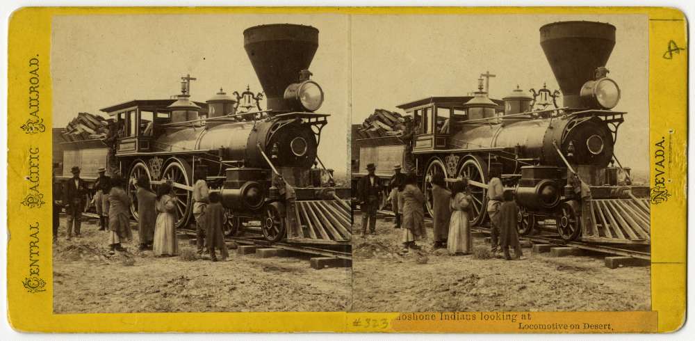 A stereo card showing members of the Shoshone Nation examining a locomotive