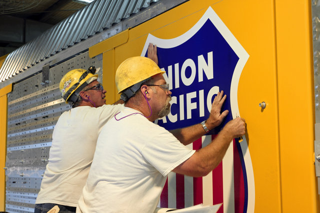 Employees Jeff Davis and Rick Bowen apply decals to an Auto Flex convertible multi-level rail car at Desoto Car Shop, in Desoto, Missouri.