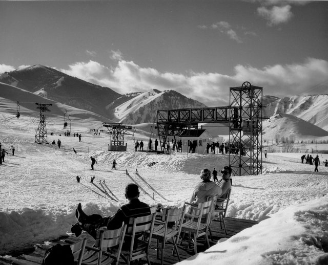 Sun Valley resort in the winter of 1937. This image shows the newly installed chair lift in action taking skiers up the mountain in front of spectators.