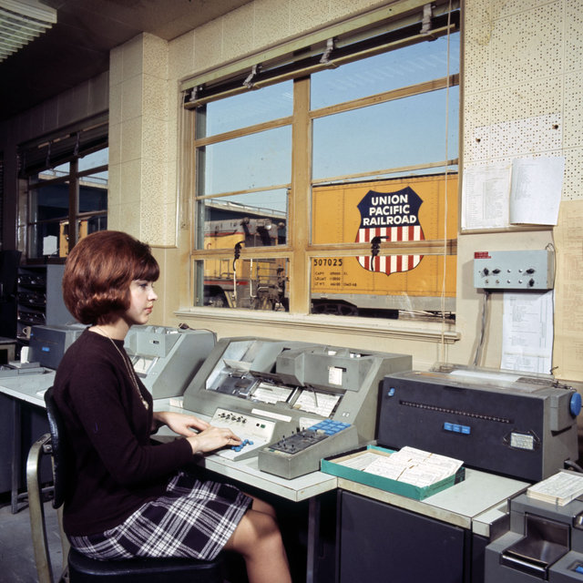 Color photograph showing a female railroad employee at the East Los Angeles, California Yard Office in March of the year 1969.