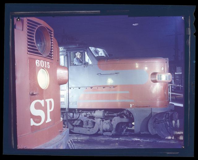 A night shot of engine locomotives at night, West Oakland, CA, data unknown. Southern Pacific engine no. 6015 is on the left.
