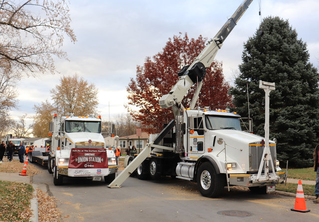 A Union Pacific boom truck and lowboy truck position to safely transport Omaha’s official Christmas Tree, a 5,500-pound blue spruce donated from the front yard of a metro-area home.  