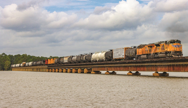 A Union Pacific train carrying mixed freight passes over a lake.