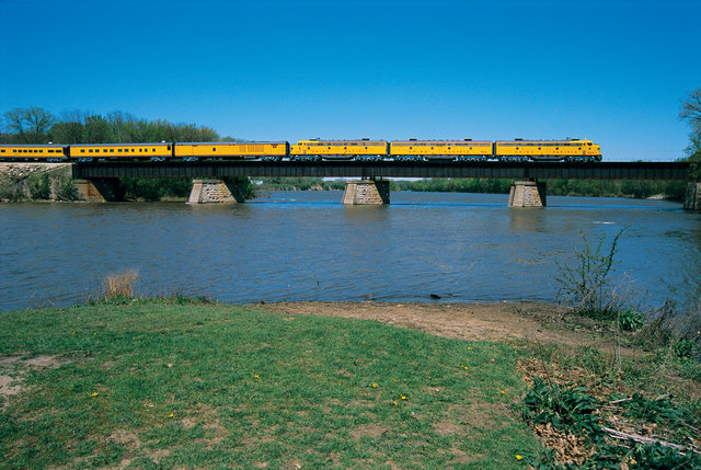 Union Pacific freight train locomotive traveling on railroad tracks through a dry, open landscape, with mountains visible in the background under a clear sky.