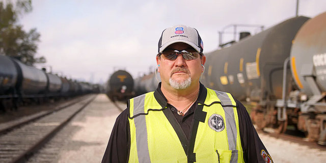 Todd Barras, locomotive engineer, Houston, stands in train yard. | LR