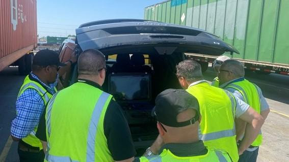 Employees viewing drone on portable monitor. | M