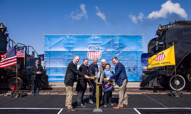 Group photo of people posing with a ceremonial gold spike commemorating the completion of the transcontinental railroad.