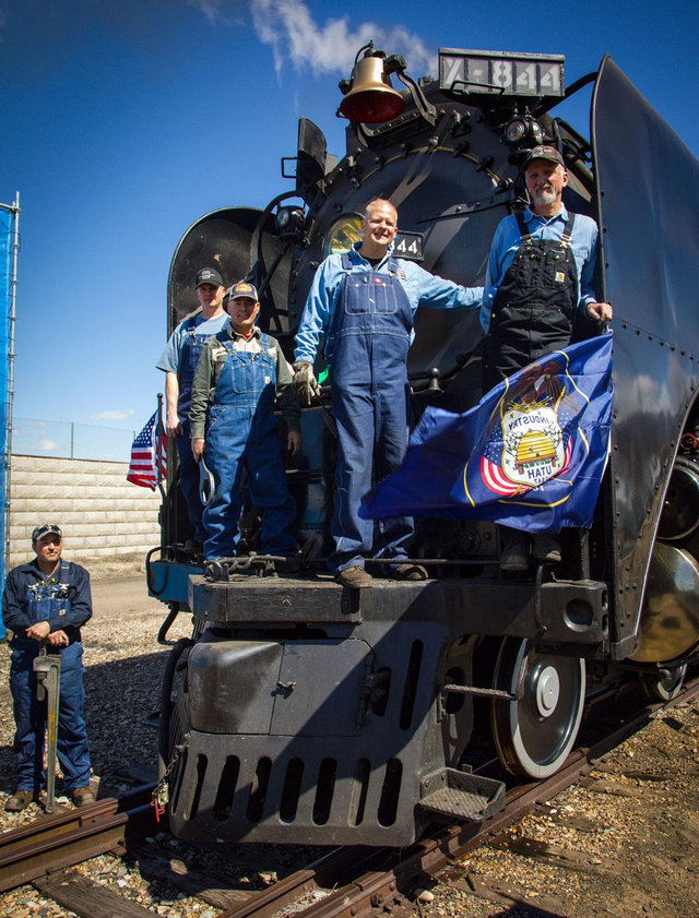 Portrait of the Union Pacific steam locomotive No. 844 crew members standing together outdoors, wearing uniforms and smiling.