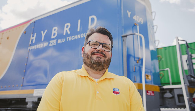 Jason Fox stands in front of a hybrid locomotive | MR