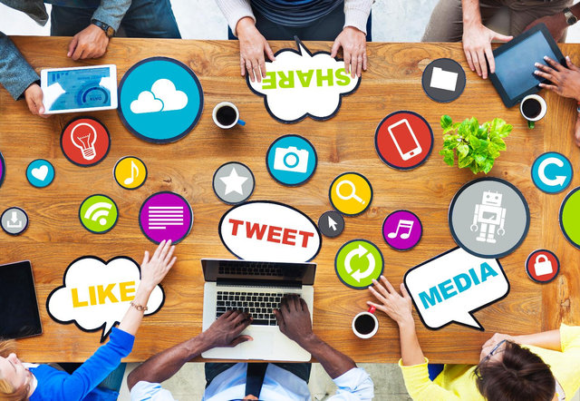A table with laptops and the hands of people working on social networks