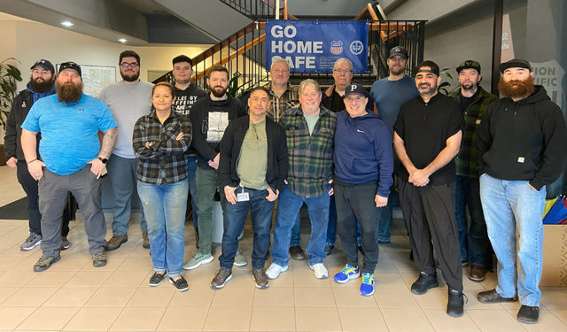 group of employees stand in front of Go Home Safe banner