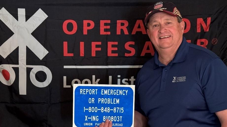 Engineer Mel Doughty with blue and white emergency sign. | L