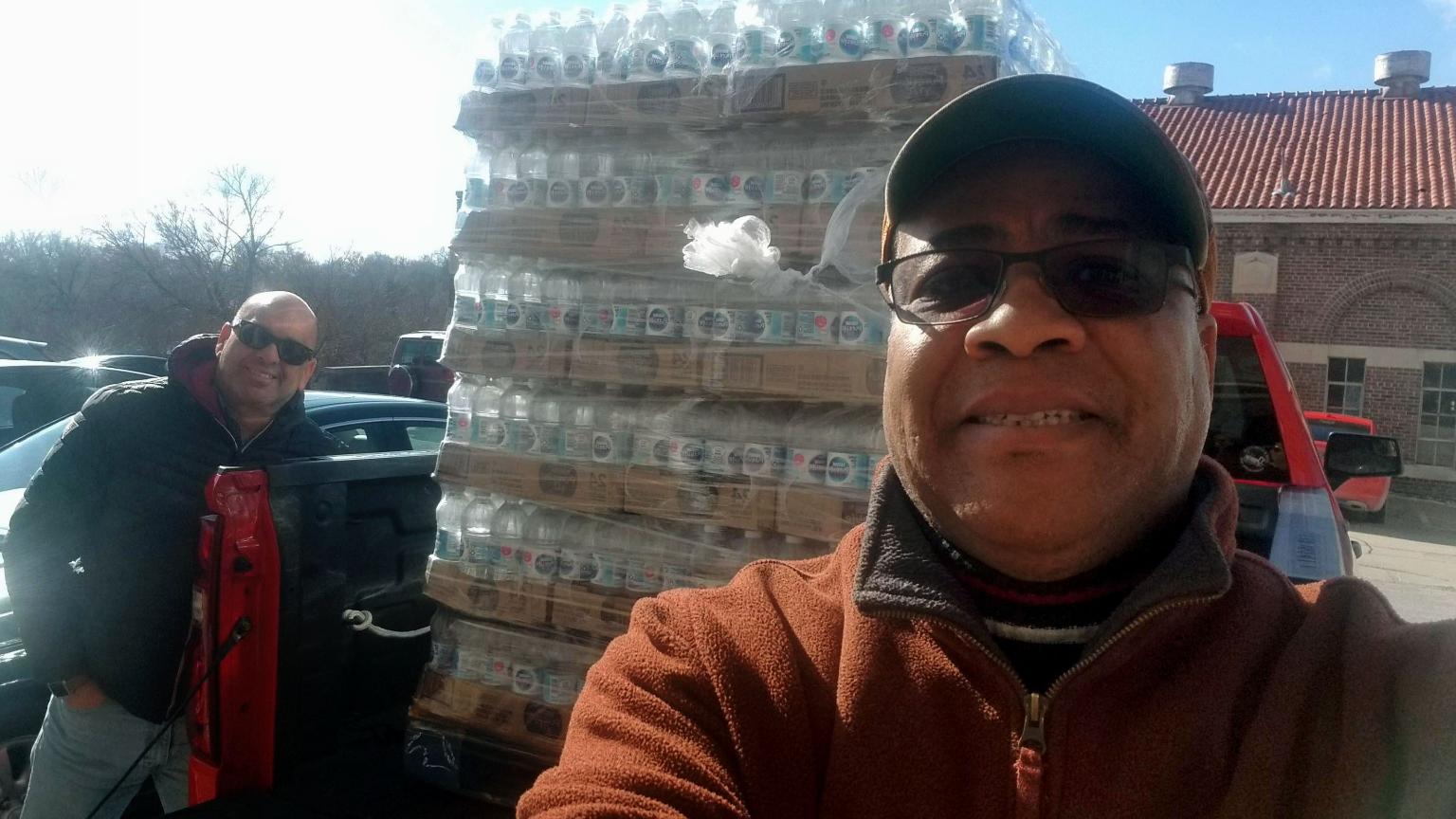 Enrique Garcia and Demetrius Watson pose in front of cases of water