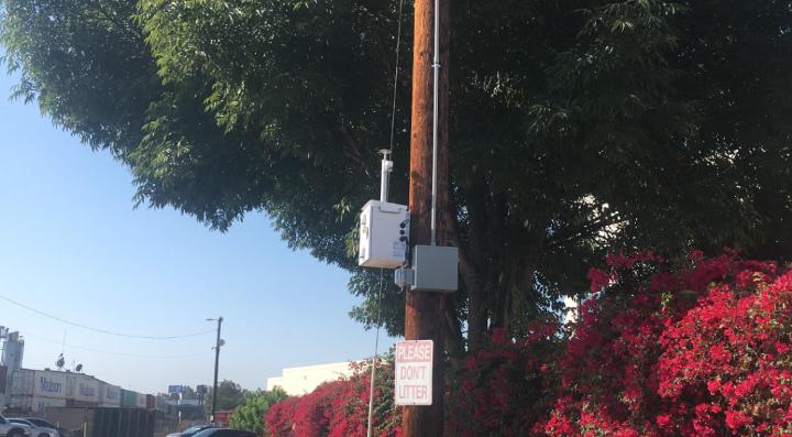 A TSI DustTrak Environmental Monitor mounted on a pole in the Dolores Locomotive Shop parking lot.