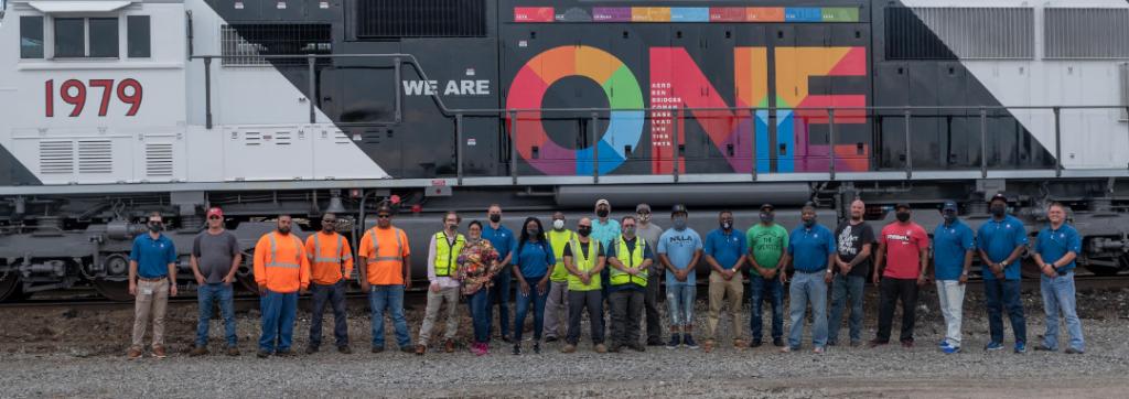 Large | Employees in New Orleans pose with the We Are ONE Locomotive.