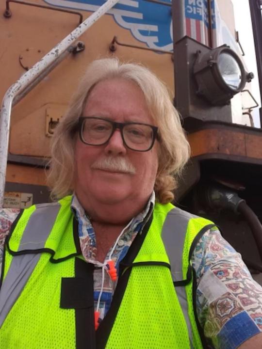A recent photo of Guerin standing in front of a locomotive.