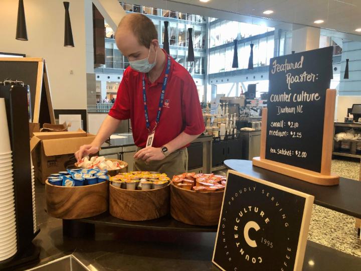 Medium | Alex Dick restocking coffee creamer in the UP Cafe.