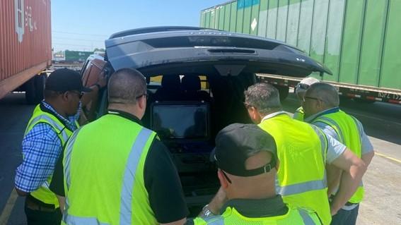 Employees viewing drone on portable monitor. | M