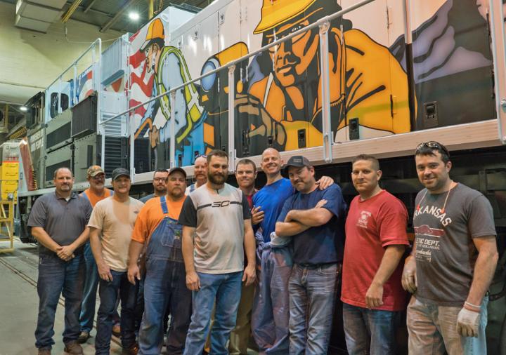 Jenks Shop employees who blasted, sanded, stripped, painted and decaled the Employee Pride Locomotive take a photo before it pulls out of the shop.