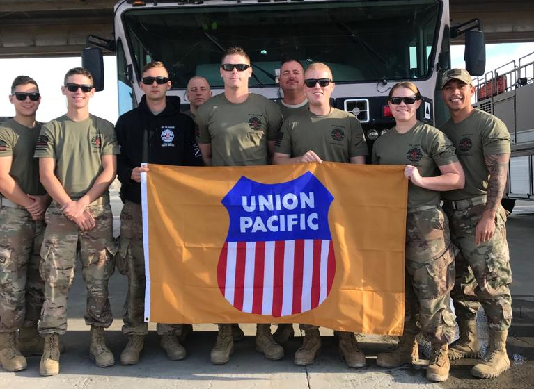 Brakeman Chris Tinsley, center, and his fellow firefighters hold a Union Pacific flag while deployed.