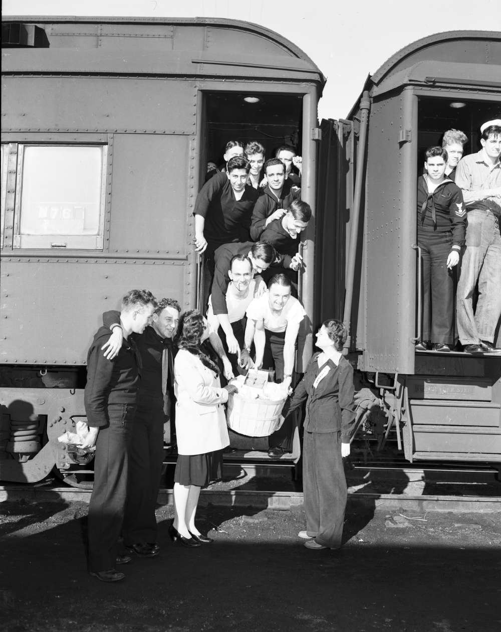 Soldiers pile in doorway of troop train to receive a basket in North Platte, Nebraska