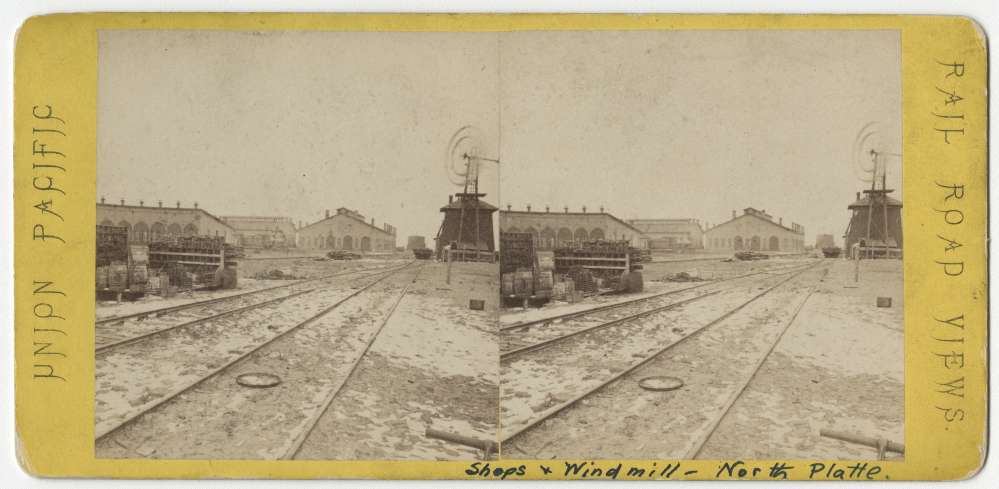 A stereo card showing shops and a windmill in North Platte, Nebraska