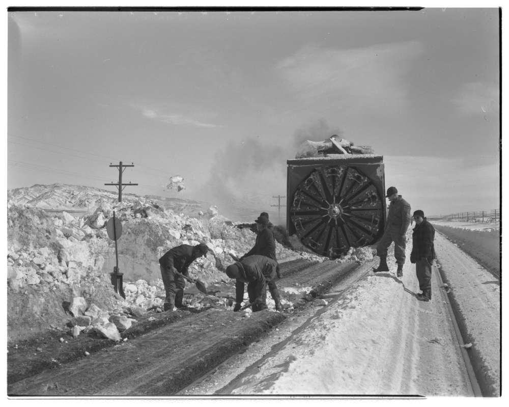 Employees dig out switch buried in snow for incoming rotary snow plow in Rawlins, Wyoming